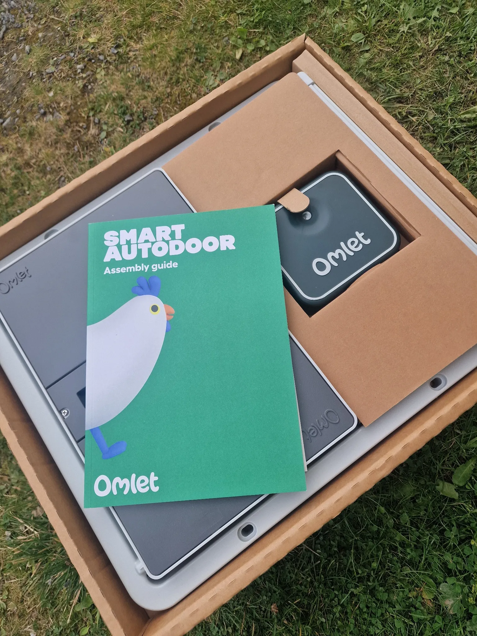 Omlet Smart Autodoor i esken med monteringsveiledningen øverst.